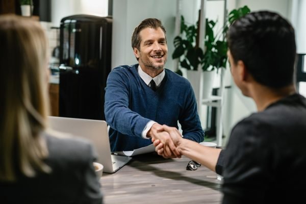 happy-financial-consultant-greeting-his-clients-while-meeting-them-their-home-me-are-shaking-hands